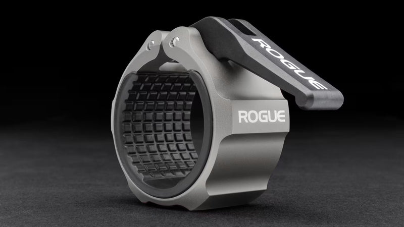 ROGUE USAアルミニウムカラー 2.0 シルバーを斜め前方から捉え、ロックオープンナイロンレバーとCNC加工アルミボディ、内側ラバーライニング構造が分かるオリンピックバーベル用カラー