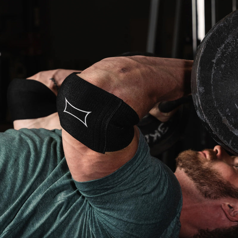 SLINGSHOT ビギー コンプレッションカフ ブラックをベンチプレス動作中の肘に着用。曲げた状態での安定感とサポート性能が伝わる視点