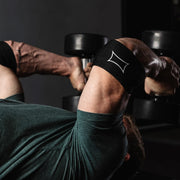 SLINGSHOT コンプレッションカフ ブラックを着用した腕を下から見上げる角度で捉え、肘周囲の圧迫サポートと筋肉の動きが分かる構図