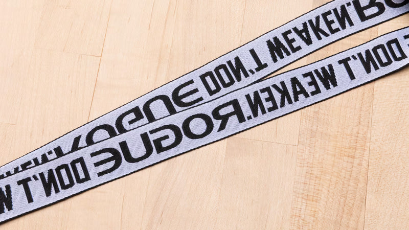 ROGUE ランヤード Don't Weaken ブラックのストラップ部分を上方からクローズアップした構図。DON'T WEAKEN.ROGUEのロゴプリントと織りストラップ素材の質感が分かるディテール