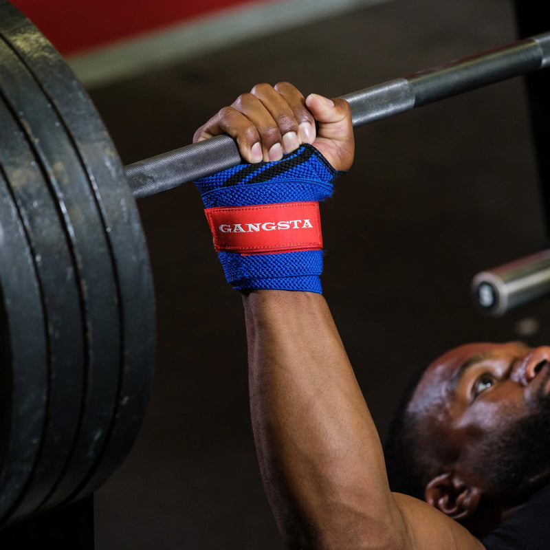 SLINGSHOT ギャングスタ リストラップ ブルーを装着しバーベルを握る斜め下角度、手首から前腕のサポート状態が分かるベンチプレス時のリストラップ