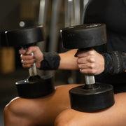 SLINGSHOT ギャングスタ リストラップ ブラックカモを装着しダンベルを握る斜め前角度、手首から前腕のサポート状態が分かるトレーニングシーンのリストラップ