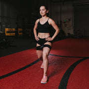 SLINGSHOT ヒップサークル ブラックを両太ももに装着し、直立姿勢で下半身全体を捉えた視点。ヒップバンドのフィット位置が分かる構図