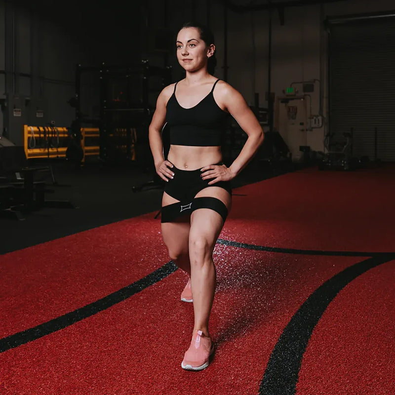 SLINGSHOT ヒップサークル ブラックを両太ももに装着し、直立姿勢で下半身全体を捉えた視点。ヒップバンドのフィット位置が分かる構図