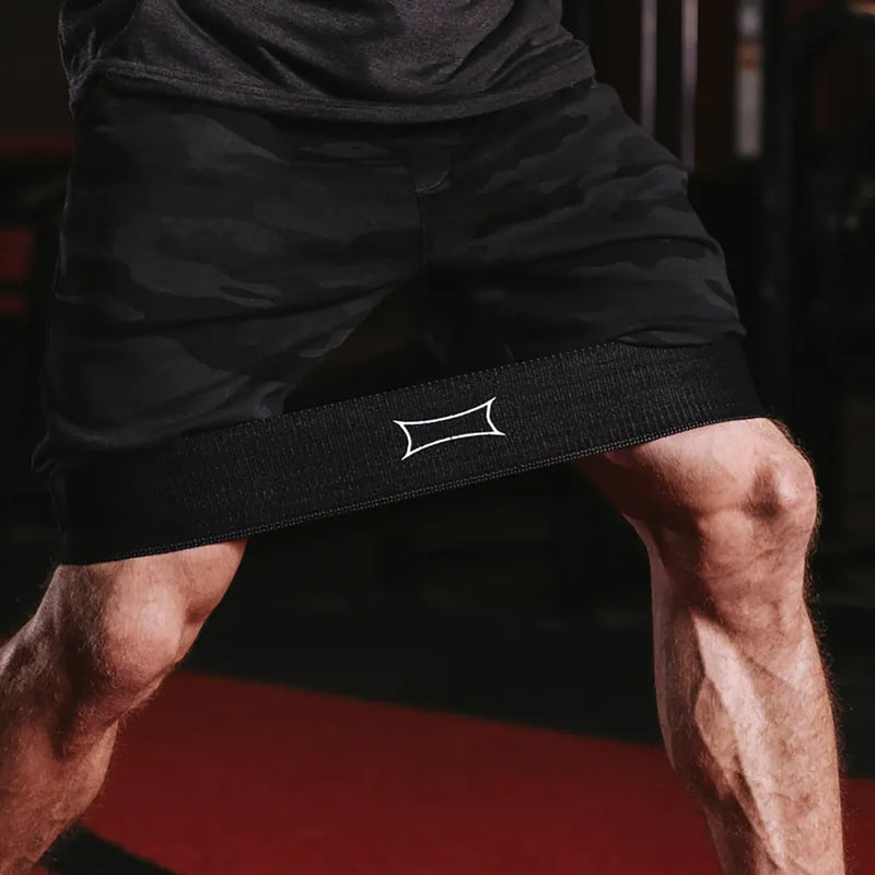 SLINGSHOT ヒップサークル ブラックを太ももに装着し、スクワット姿勢で下半身をクローズアップした視点。バンドの張力と装着位置が分かる構図