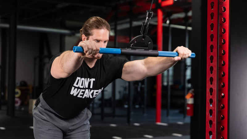 Mutant Metals ARC ケーブルアタッチメント ブルーを使用したケーブルフロントレイズ動作、両腕を前方へ伸ばした姿勢とブルーグリップの握り幅が分かる構図