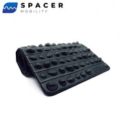 黒のROCK MATを斜め前から見た状態で、折り畳み可能な構造と表面に配置された多数の突起形状が分かる構成により、全体フォルムと厚みのバランスを確認できるモビリティ用フットケアマット