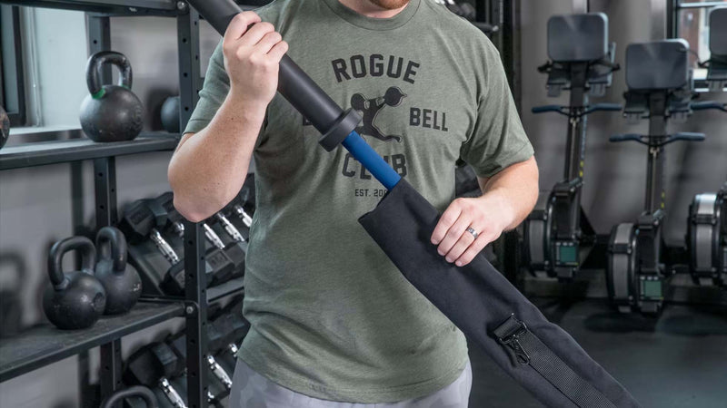 ROGUE バーベルキャリーバッグ20KG ブラックの使用例。開口部からバーベルを収納する様子を正面寄りから捉え、バッグの構造と収納方法を確認可能