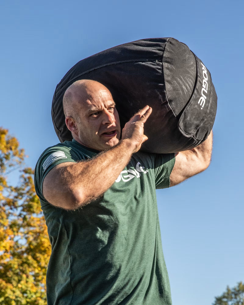 ROGUE エコーストロングマンサンドバッグ ブラック 肩に担ぎ上げた横からのアングル、屋外トレーニング動作が分かるカット