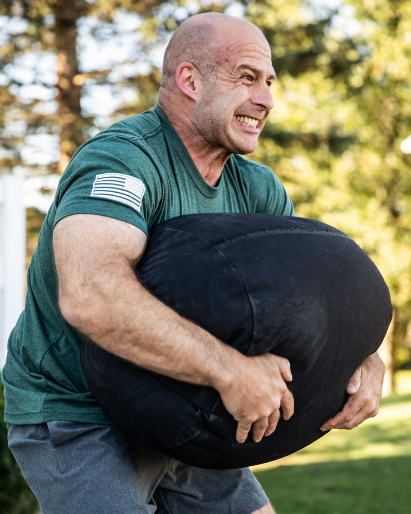 ROGUE エコーストロングマンサンドバッグ ブラック 横から抱え込む斜めアングル、体幹トレーニング動作が伝わる構図