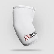SLINGSHOT ストロング エルボースリーブ ホワイトの単体製品を斜め前方から捉えた構図。肘部分の立体カーブ形状と縫製ライン、STRONGロゴ位置が分かる視点