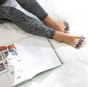 黒のThe Toe Spacerを装着したまま仰向けでリラックスしている状態を斜め上から捉え、足指を自然に広げたままコンディショニングを行うモビリティケア時の使用シーン