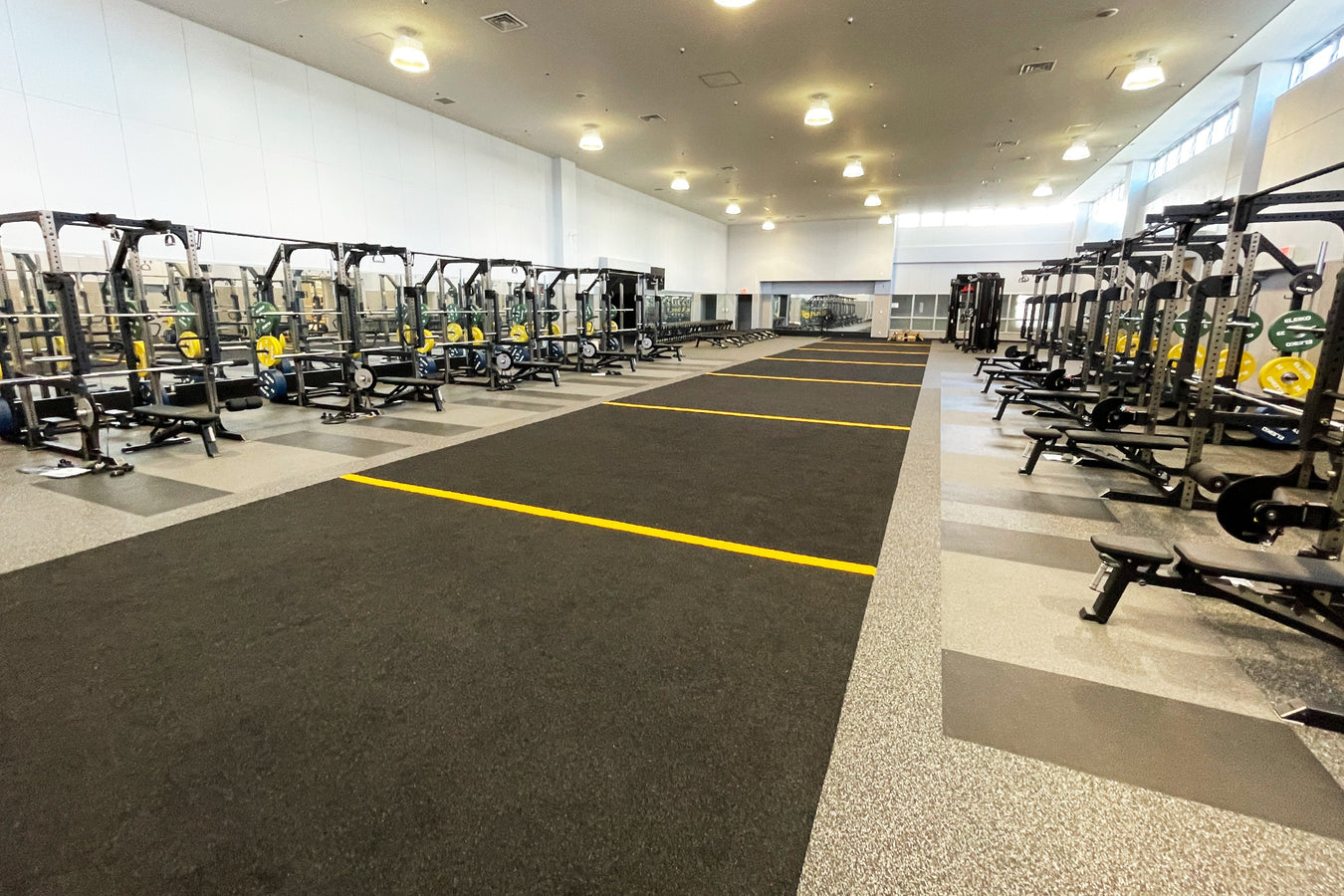 広いフリーウェイトジム内に人工芝レーンが設置された空間を斜めから捉えた、トレーニングエリア全体のレイアウト