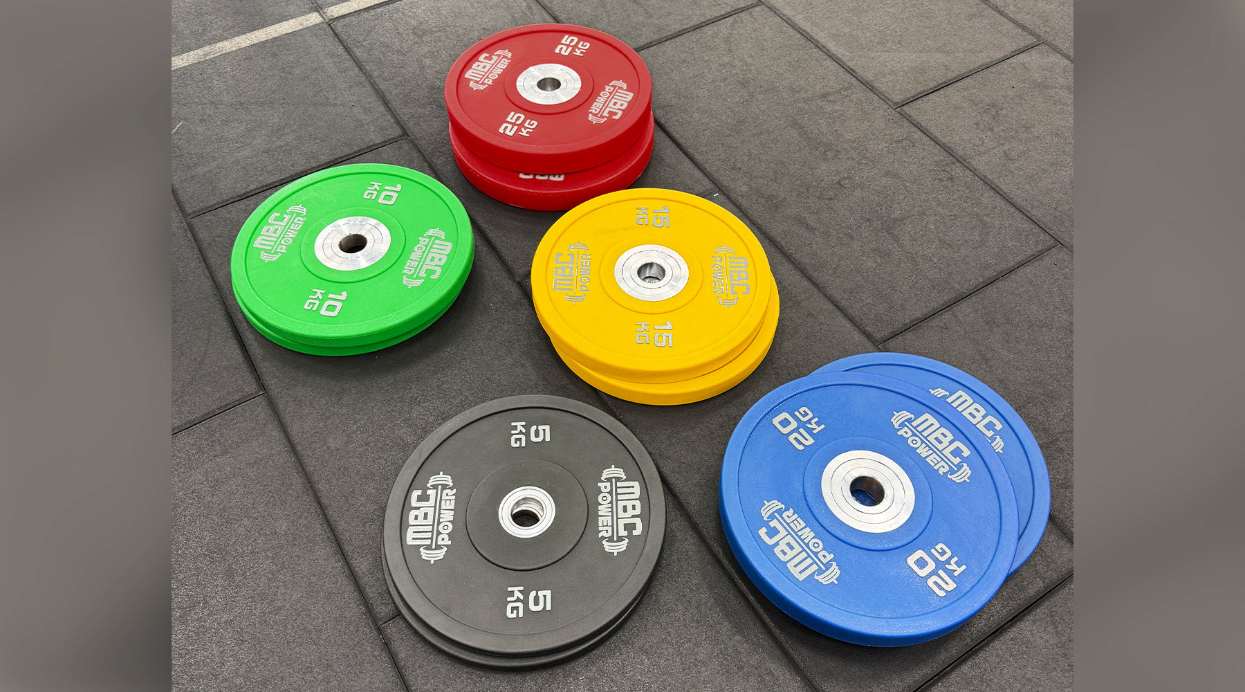 MBC ウレタンバンパープレート ブルー 20kgとイエロー 15kgを手前に配置し複数カラーを奥に並べた俯瞰構図、重量ごとの色分けが分かる視点